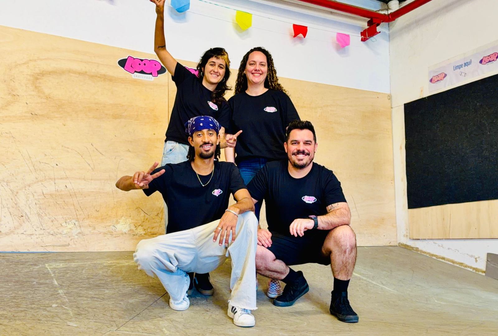 Os quatro fundadores da Loop Skate Park reunidos na pista, de camiseta preta com o logo da Loop